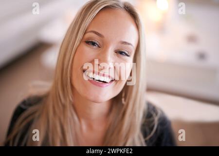 Felice, ritratto e donna in una casa rilassarsi con fiducia, atteggiamento positivo o sentirsi di buon umore a casa sua. Faccia, sorriso e persona femminile in vita Foto Stock