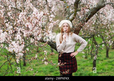 godetevi la primavera e passeggiate all'aria aperta. Bella donna che cammina nel giardino degli alberi primaverili. Foto Stock