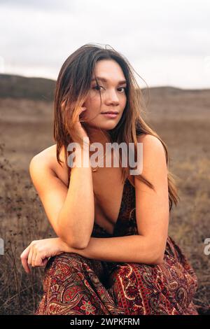 Donna multirazziale che indossa un vestito seduto fuori pista a San Diego Foto Stock