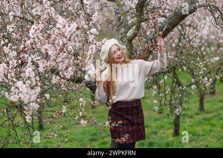 Primavera in arrivo. Bella donna che cammina nel giardino degli alberi primaverili. Concetti di stile di vita per le persone di bellezza. Foto Stock