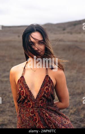 Donna multirazziale in piedi sul campo con i capelli che soffiano sul viso Foto Stock