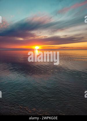 Il Sole si trova sotto l'Horizion su un lago blu Foto Stock