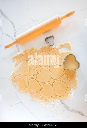 Vista dall'alto dell'impasto tagliato a forma di cuore sul banco di marmo. Foto Stock