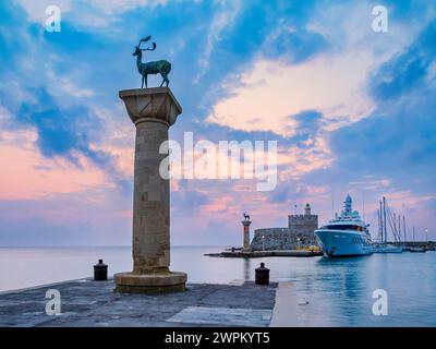 Cervi e cervi sulle colonne all'ingresso del Porto di Mandraki, ex sede del Colosseo di Rodi, la Fortezza di San Nicola sullo sfondo Foto Stock
