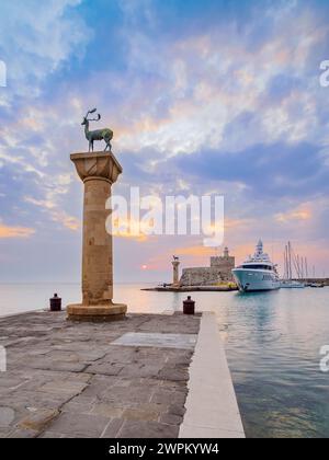 Cervi e cervi sulle colonne all'ingresso del Porto di Mandraki, ex sede del Colosseo di Rodi, la Fortezza di San Nicola sullo sfondo Foto Stock