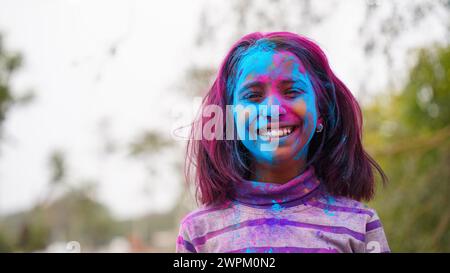 Amici indiani felici o bambini che celebrano il festival indù di Holi applicando i colori l'uno all'altro, migliori amici. Fratelli e sorelle che tengono un piatto wi Foto Stock