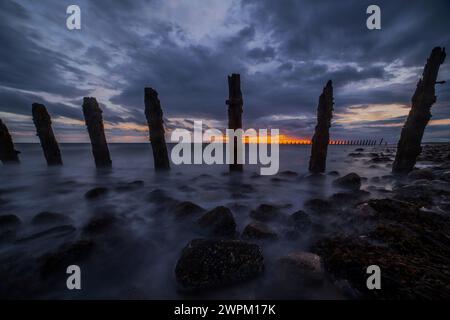 Nuvole di tempesta si riuniscono sul Mare d'Irlanda, indossando difese marittime da South Walney al tramonto dalla costa della Cumbria, Inghilterra, Regno Unito Foto Stock