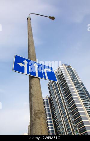 Cartello stradale con frecce sullo sfondo della città da vicino Foto Stock