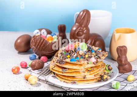 La colazione per i bambini è divertente e carina per Pasqua. Frittelle americane, torte fritte con uova di cioccolato pasquale, marshmallows, farcitura di zucchero con rotto Foto Stock