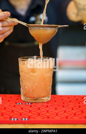 Barman che prepara un cocktail e versa una bevanda in un bicchiere Foto Stock