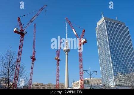 La famosa torre della televisione di Berlino, un grattacielo e quattro gru a torre rosse Foto Stock