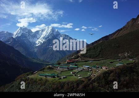 Escursioni in Nepal, Himalaya, piccolo aereo che vola sopra il villaggio di Dhole (4200 m), montagna di Thamserku sullo sfondo. Sentiero da Namche a Gokyo Foto Stock