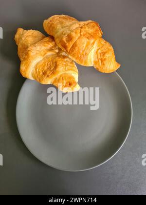 Due croissant su un piatto grigio come spuntino veloce tra i pasti Foto Stock