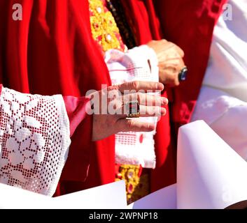 Vescovo in abito religioso rosso benedice i fedeli con mano e grande anello Foto Stock