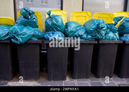 Germania, Baviera, Norimberga, lattine di immondizia, una accanto all'altra, sacchi di immondizia blu pieni Foto Stock