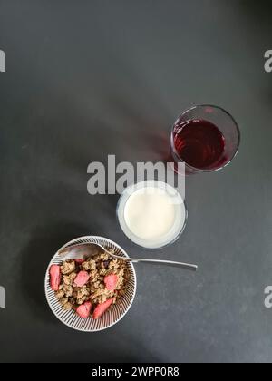 Una ciotola di muesli di grano con fragole e due bicchieri di succo e latte tra cui scegliere Foto Stock