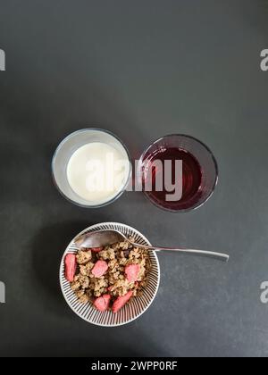 Una ciotola di muesli di grano con fragole e due bicchieri di succo e latte tra cui scegliere Foto Stock