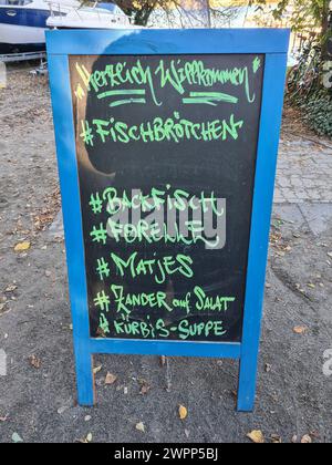 Un cartello pubblicitario a Wannsee pubblicizza panini di pesce, pesce fritto, trota, matjes, luccio-perch sull'insalata e zuppa di zucca in scrittura a mano sul suo cartellone Foto Stock