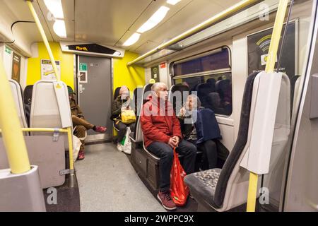 Passeggeri che viaggiano su un treno Merseyrail classe 507 che mostra i passeggeri e l'interno del treno Foto Stock