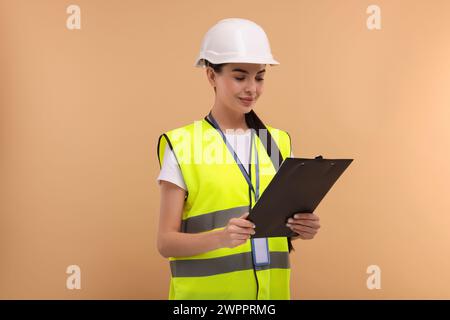 Ingegnere in elmetto che regge gli appunti su sfondo beige Foto Stock