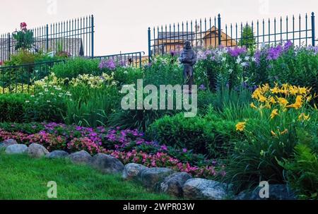 Statua di St Francesco d'Assisi tra i bellissimi gigli e le piante in fiore in una serata estiva ai Giardini della Valle di Panola, una location per matrimoni. Foto Stock