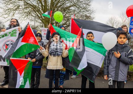 Bingley, Regno Unito. 08 MAR, 2024. Una ragazza fa sventolare due bandiere palestinesi insieme ad altri alunni della scuola elementare del villaggio di Cottingley. Storia: I genitori degli studenti della Cottingley Village Primary School hanno tirato fuori i loro figli alle 14:00 dell'8 marzo come parte di uno sforzo coordinato di sciopero in più scuole diverse in tutto lo Yorkshire per la Palestina. Credito Milo Chandler/Alamy Live News Foto Stock