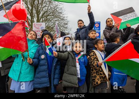 Bingley, Regno Unito. 08 MAR, 2024. Gli studenti del villaggio di Cottingley bandiere d'onda primarie fuori dai cancelli principali. Storia: I genitori degli studenti della Cottingley Village Primary School hanno tirato fuori i loro figli alle 14:00 dell'8 marzo come parte di uno sforzo coordinato di sciopero in più scuole diverse in tutto lo Yorkshire per la Palestina. Credito Milo Chandler/Alamy Live News Foto Stock