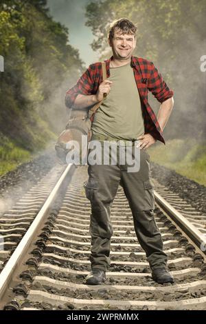 Avventuriero con l'haversack retrò che vagava nella natura sulla ferrovia Foto Stock