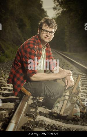 Avventuriero con l'haversack retrò che vagava nella natura sulla ferrovia Foto Stock