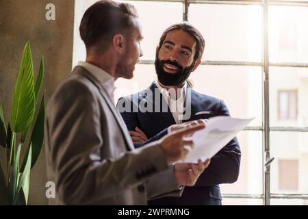 Colleghi aziendali che discutono di documenti in un ambiente luminoso, impegnati in una revisione collaborativa del lavoro. Foto Stock