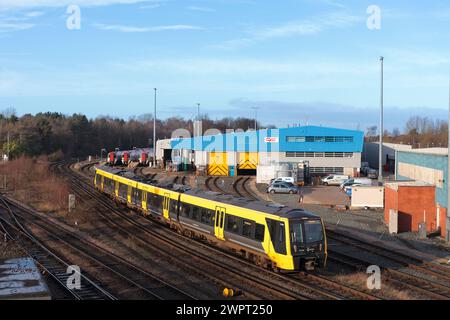 Merseyrail Stadler classe 777 3rd treno elettrico 777030 a Chester passando per il deposito di manutenzione dei treni CAF con la classe 197 stazionata Foto Stock