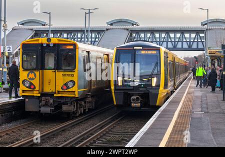 Nuovi e vecchi treni Merseyrail che passano a Hooton, classe 507 (vecchio) a sinistra, classe 777 (nuovo) a destra Foto Stock