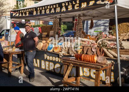 Un uomo italiano con la sua tradizione di formaggi, salumi e salumi secchi, mercato delle Fauche, un grande mercato all'aperto a Milano, Italia. Foto Stock