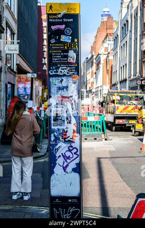 Soho, Londra Regno Unito, 08 marzo 2024, Anonymous Woman Back to camera Standing Next to Graffiti vandalizzato Direction Street Map Foto Stock