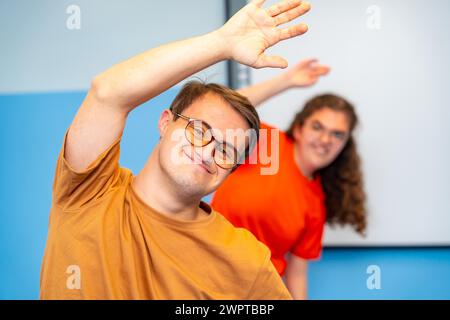 Uomo con sindrome di Down che si allunga e si allena con gli amici in palestra Foto Stock