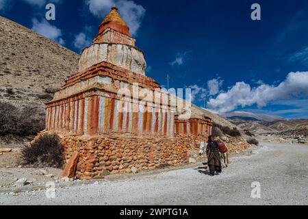 Donna con il suo cavallo, stupa buddista colorato di fronte al paesaggio di montagna, al paesaggio erosivo e alle case di Garphu dietro, Garphu Foto Stock