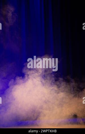 Pennacchi di fumo alla luce dei faretti sullo sfondo di una tenda sul palco. Foto Stock