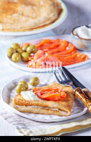 Pancake con gravlax, formaggio fresco e olive. Un piatto tradizionale per Maslenitsa o Carnevale. Foto Stock