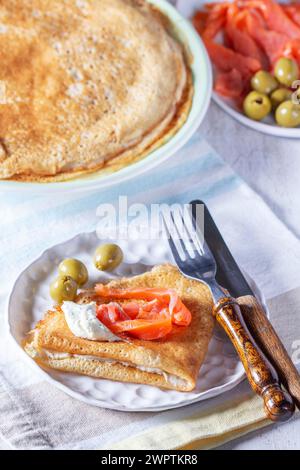 Pancake con gravlax, formaggio fresco e olive. Un piatto tradizionale per Maslenitsa o Carnevale. Foto Stock