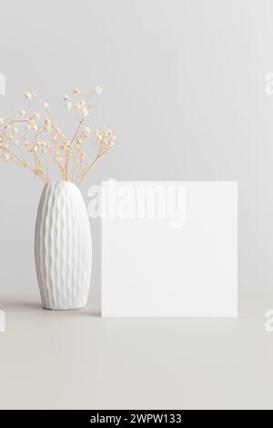 Immagine con carta d'invito quadrata con una gypsophila su un tavolo beige. Foto Stock