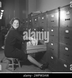 Una donna lavora in un archivio nel 1942. La signora Ingrid Welin, un dipendente dell'Ufficio degli interessi dello Stato, sfoglia i documenti dell'archivio. L'ufficio interessi aveva sede a Postgirohuset a Stoccolma e mirava ad aiutare il bilancio dei suoi 80.000 membri e a pagare le loro tasse, affitti, assicurazioni, ecc.. Svezia 1942. Kristoffersson rif. B89-5 Foto Stock
