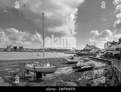 Immagine monocromatica del lungofiume di Torpoint, nel sud-est della Cornovaglia, con barche ormeggiate sulla spiaggia. Dall'altra parte del fiume Tamar si trova l'arsenale di Devonport Foto Stock