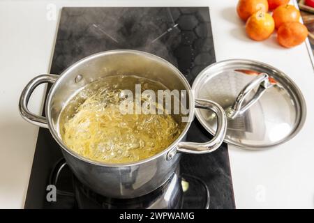 Una pentola in acciaio inox riempita con acqua bollente per cucinare la pasta al dente Foto Stock