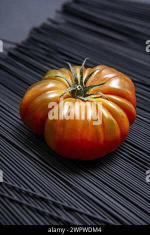 Succulenti pomodori Raf maturi su spaghetti di colore nero Foto Stock