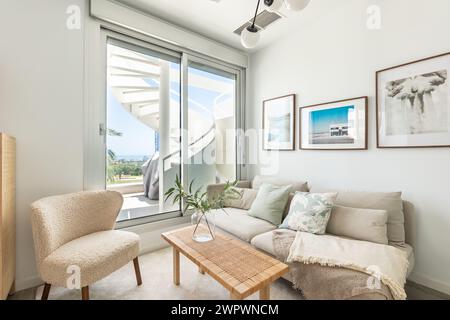 immagine di un divano e di una sedia nello spazio del soggiorno che conduce alla scala a chiocciola sulla terrazza dell'appartamento mediterraneo Foto Stock