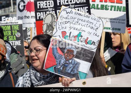 Londra, Regno Unito. 9 marzo 2024. Donna con un poster di Nelson Mandela, Un'enorme marcia pacifica verso l'ambasciata degli Stati Uniti richiede un cessate il fuoco a Gaza e la fine del genocidio israeliano. L'IDF ha ora ucciso oltre 30.000 persone, soprattutto donne e bambini, continuano a ignorare la sentenza della Corte di giustizia per evitare il genocidio e preparare un brutale assalto a Rafah. Israele continua a fermare gli aiuti umanitari e le forniture mediche necessarie per evitare morti di massa per malattie e fame e diffonde bugie sull'UNRWA, il cui finanziamento è essenziale. . Peter Marshall/Alamy Live News Foto Stock