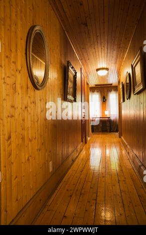 Corridoio con pavimento in legno duro al piano superiore all'interno di una vecchia casa a due piani degli anni '1920. Foto Stock