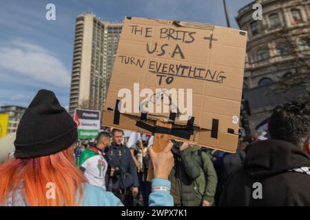 Londra, Regno Unito. 9 marzo 2024. Un manifestante con i capelli arancioni ha un cartello fatto a mano con la scritta "THE BRITS + U.S.A TURN EVERYTHING TO [drawing of feces]" durante una dimostrazione a Londra. Altri cartelli fanno riferimento alla Palestina, alla solidarietà e alla libertà. La scena cattura il dissenso politico e l'espressione pubblica in un ambiente urbano. Migliaia di persone si riuniscono a Hyde Park Corner per poi marciare verso l'ambasciata americana, per chiedere un cessate il fuoco a Gaza. Penelope Barritt/Alamy Live News Foto Stock