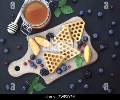 A colazione potrai gustare waffle belgi con mirtilli e miele. Deliziosa pasticceria fatta in casa. Waffle con lamponi, mirtilli, panna acida e legna Foto Stock