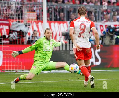 Monaco, Germania. 9 marzo 2024. Robin Zentner(L), portiere di Magonza, salva la palla da Harry Kane del Bayern Monaco durante la partita di calcio tedesca di prima divisione tra Bayern Monaco e FSV Mainz 05 a Monaco, Germania, 9 marzo 2024. Crediti: Philippe Ruiz/Xinhua/Alamy Live News Foto Stock